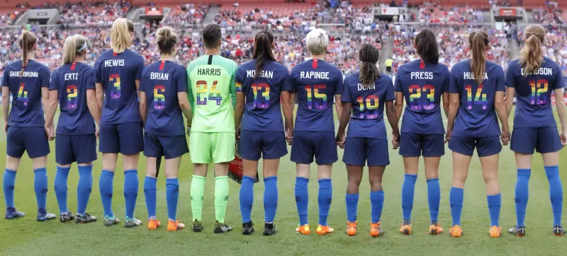 La selección femenina de Estados Unidos forma antes de un amistoso contra China disputado en Cleveland el 12 de junio de 2018, con dorsales en los colores del arcoíris.