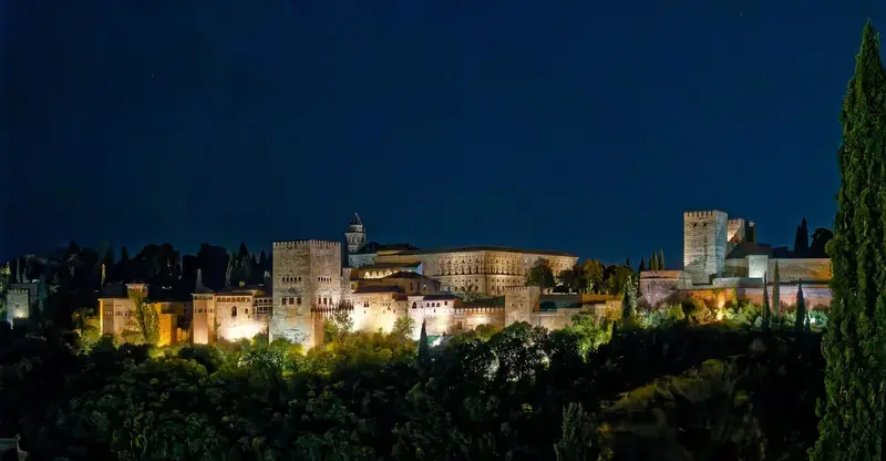 Vista de la Alhambra iluminada de noche.